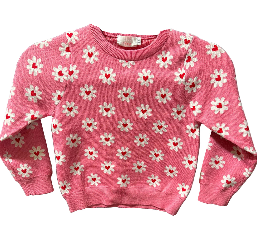 Pink sweater with white floral patterns and red centers on a black background